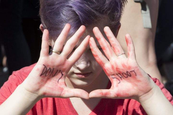 A young woman holds up her hands with words that read ‘Don’t Shoot’ as students demonstrate for stronger gun control laws outside the White House.