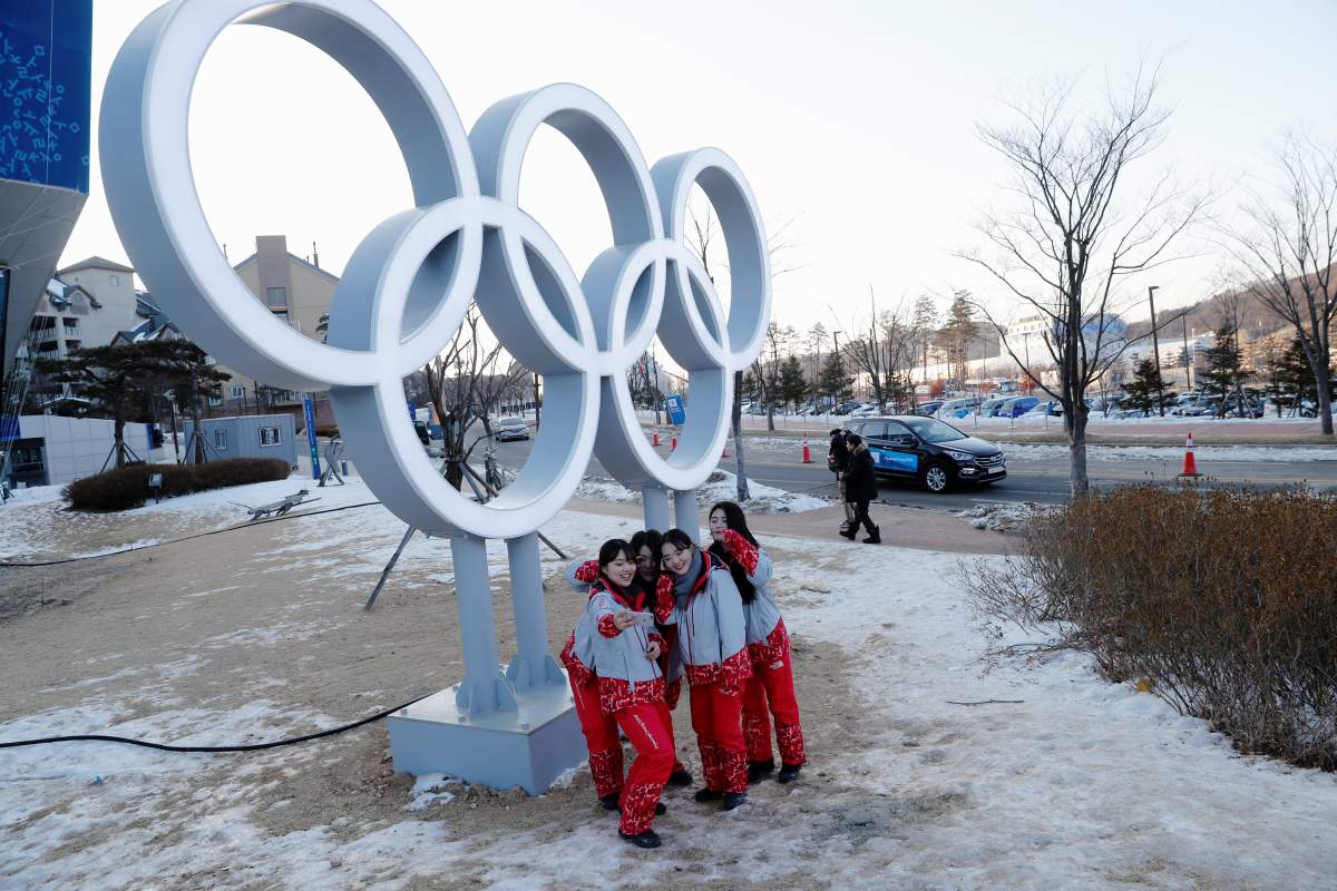 Volunteers pose next to the Olympic rings at the Pyeongchang Winter Olympic Games in Pyeongchang, South Korea February 7, 2018. 