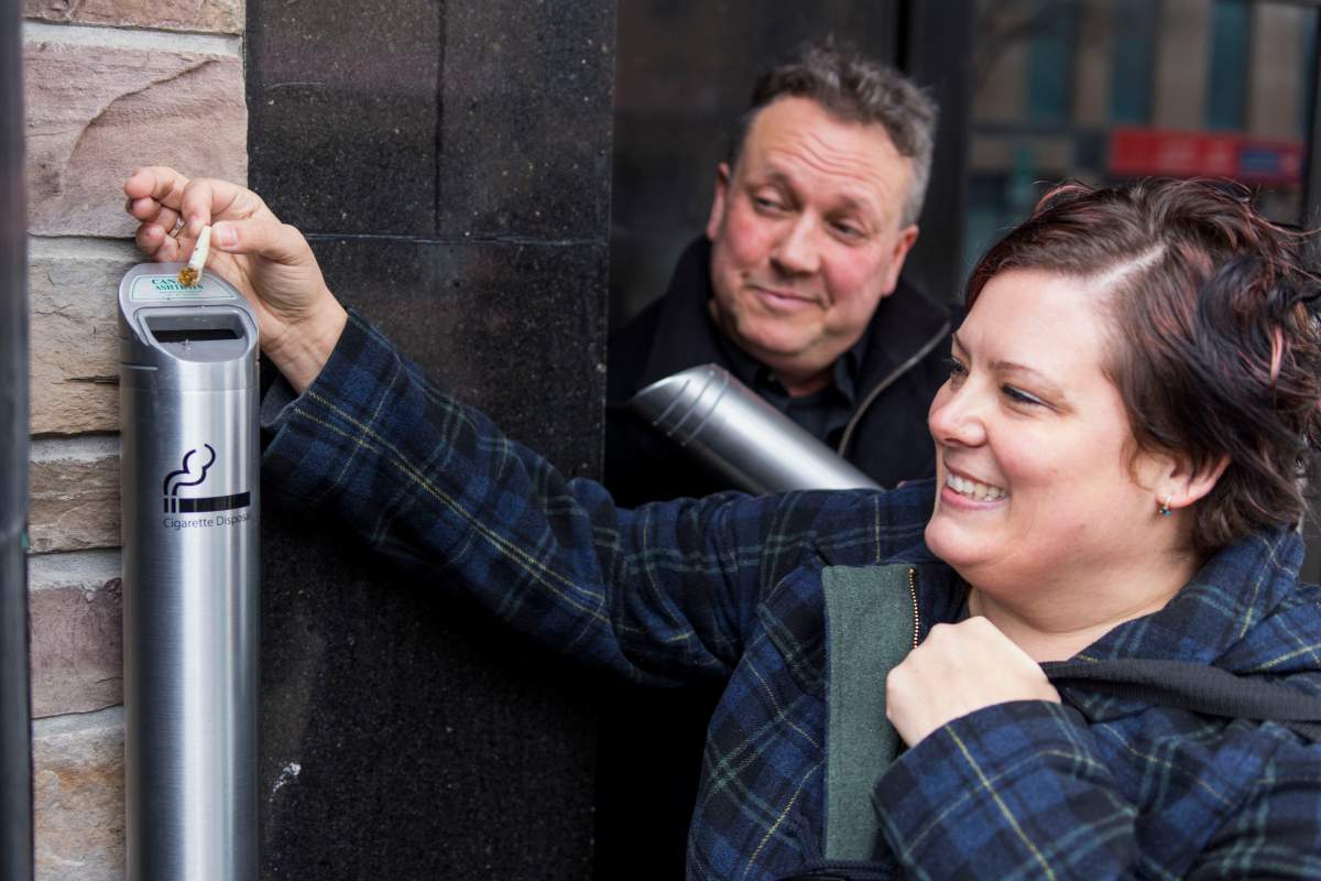 Butt 1 Community Coordinator Donna Reid and Peterborough DBIA Executive Director Terry Guiel dispose of a cigarette butt in one of the new receptacles being given away for downtown businesses.
