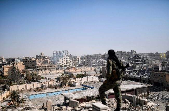 A fighter of the Syrian Democratic Forces (SDF) stands guard on a rooftop in Raqa on October 20, 2017, after retaking the city from Islamic State (IS) group fighters.


