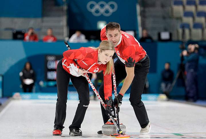 Canada's Kaitlyn Lawes and John Morris sweep the ice during the mixed doubles semi-final curling match against Norway at the 2018 Winter Olympics in Gangneung, South Korea, Feb. 12, 2018. 