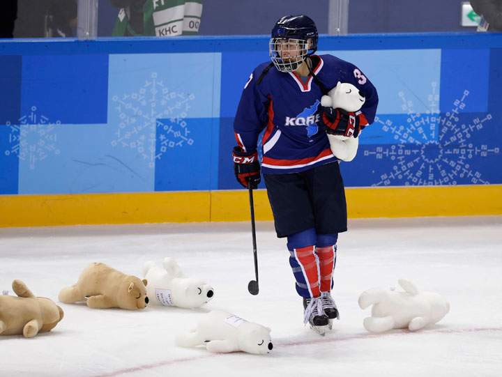 Korea’s team picks up stuffed animals tossed onto the ice after their game against Japan.