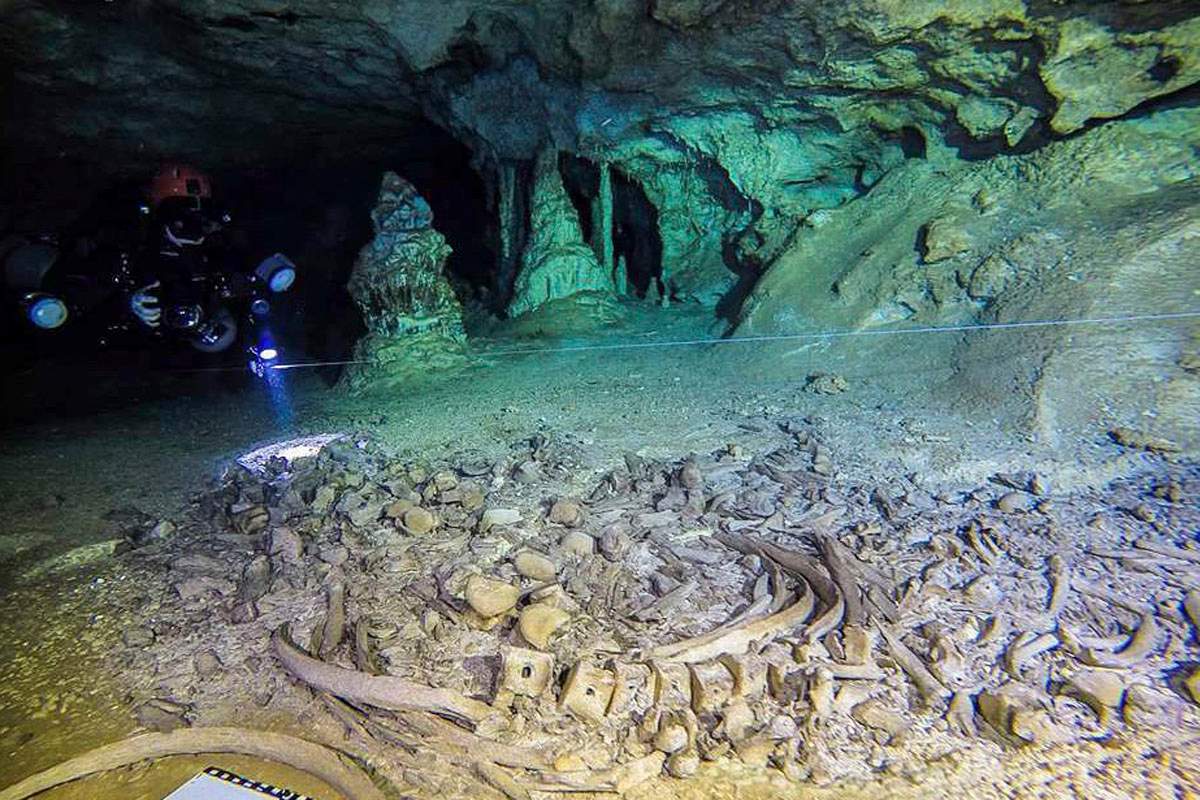 This undated photo released by Mexico’s National Anthropology and History Institute (INAH) shows divers from the Great Mayan Aquifer project, left, exploring the Sac Actun underwater cave system, where Mayan and Pleistocene bones and cultural artifacts have been found submerged, near Tulum, Mexico.