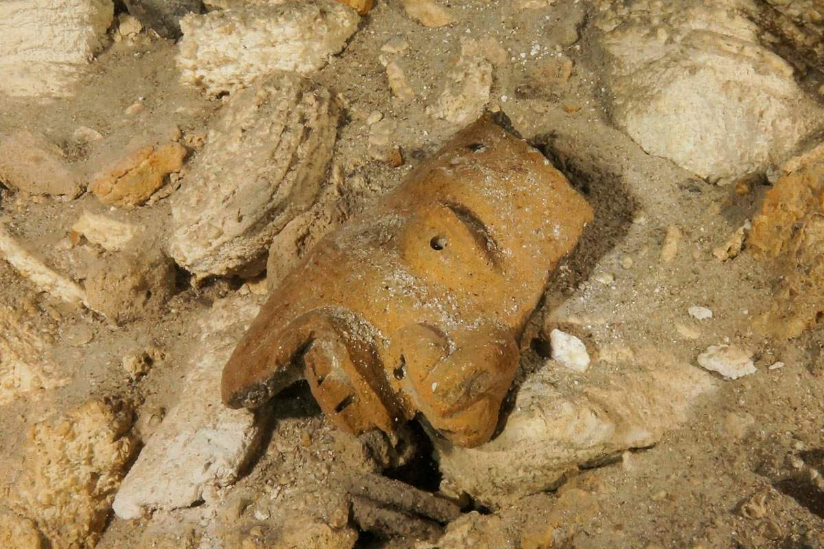 This undated photo released by Mexico’s National Anthropology and History Institute (INAH) shows a piece of a broken mask on the cave floor inside the Sac Actun underwater cave system where Mayan and Pleistocene bones and cultural artifacts have been found submerged, near Tulum, Mexico.