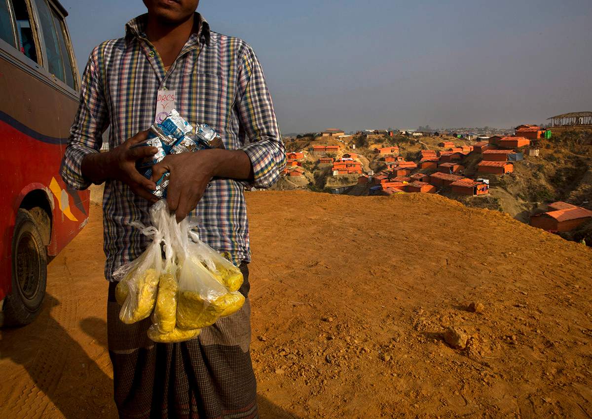 In this Wednesday, Jan. 17, 2018, photo, a newly arrived Rohingya refugee Muslim carries high power protein biscuits and Khicdhi, made from rice and lentils, for his family after arriving at Balukhali refugee camp near Cox's Bazar, Bangladesh. 