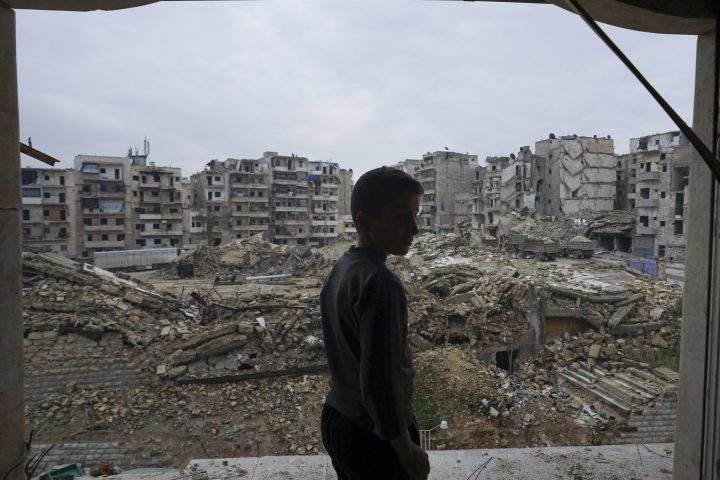 In this picture taken Sunday, Jan. 21, 2018, a resident checks the destruction from his home balcony that was damaged by shelling in Aleppo, Syria.