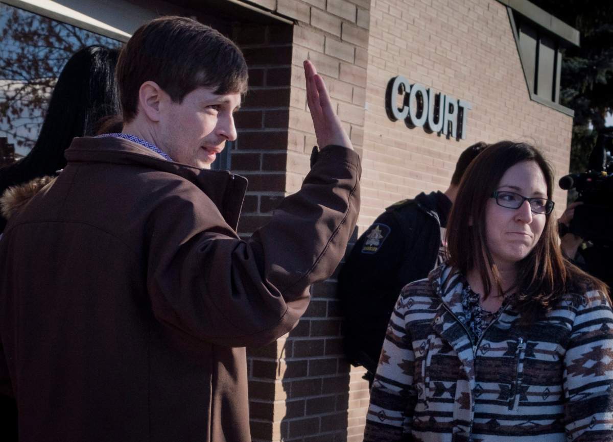 Edouard Maurice, left, waves to supporters outside court with his wife Jessica, right, in Okotoks, Alta., Friday, March 9, 2018. Maurice faces three charges after police allege the rural homeowner confronted two people rummaging through his vehicles and shots were fired.