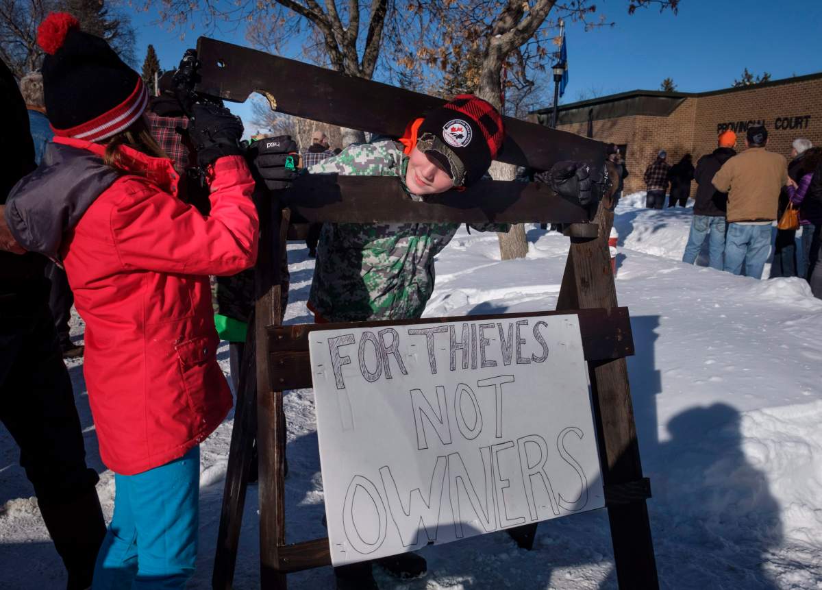 A young boy and girl play with homemade stocks as people gather in support of Edouard Maurice, who faces three charges after police allege the rural homeowner confronted two people rummaging through his vehicles and shots were fired, outside court in Okotoks, Alta., Friday, March 9, 2018.