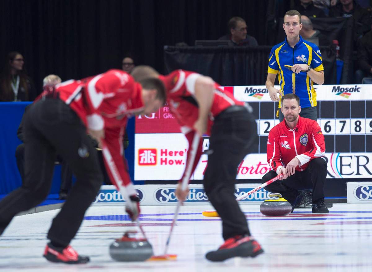 Alberta skip Brendan Bottcher, top, and Team Canada skip Brad Gushue watch as Team Canada sweeps a rock in the Tim Hortons Brier championship game at the Brandt Centre in Regina on Sunday, March 11, 2018.