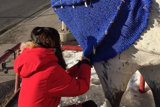 ACAD student Yilu Xing making alterations on the sweater made for the chicken statue outside of Chicken on the Way in Kensington.