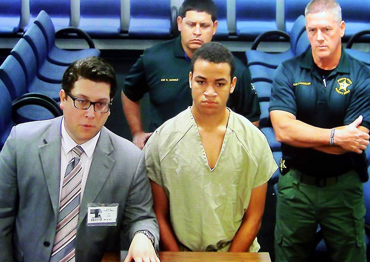 Zachary Cruz, center, the brother of the Florida school shooting suspect, is displayed in a monitor via closed circuit television from the main jail as he as he makes his first appearance on charges of trespassing on the grounds of Marjory Stoneman Douglas High School, Tuesday, March 20, 2018, at the Broward County Courthouse in Fort Lauderdale, Fla. 