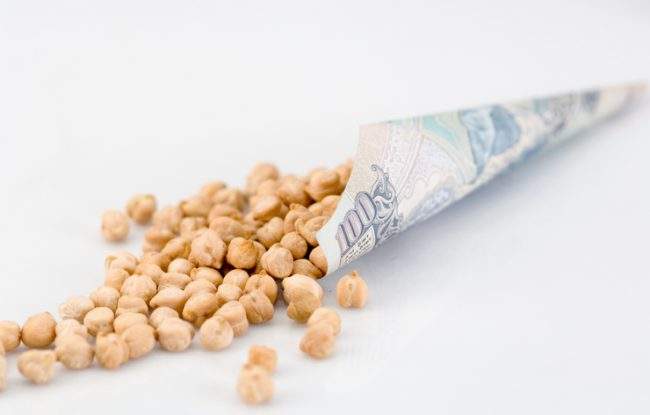 Chickpeas spill out of an Indian banknote.