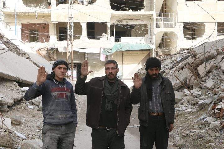 Syrian men raise their hands as they pose for a photo for #Iamstillalive.
