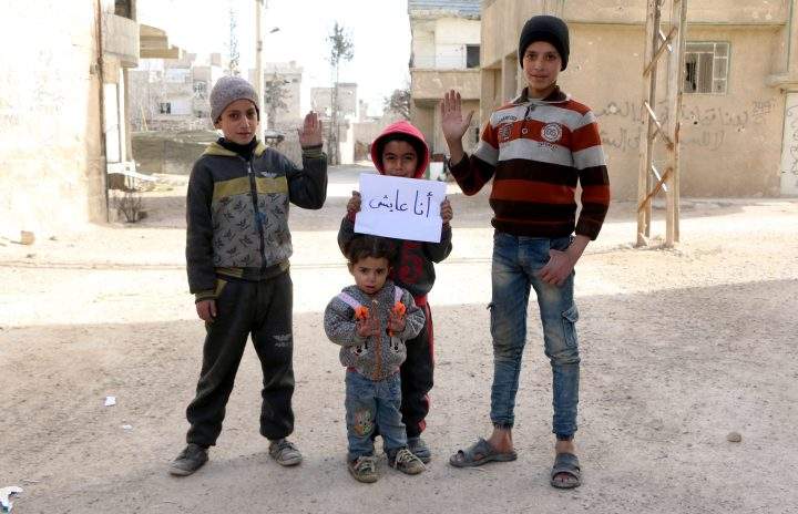 Syrian children raise their hands as part of an awareness campaign.