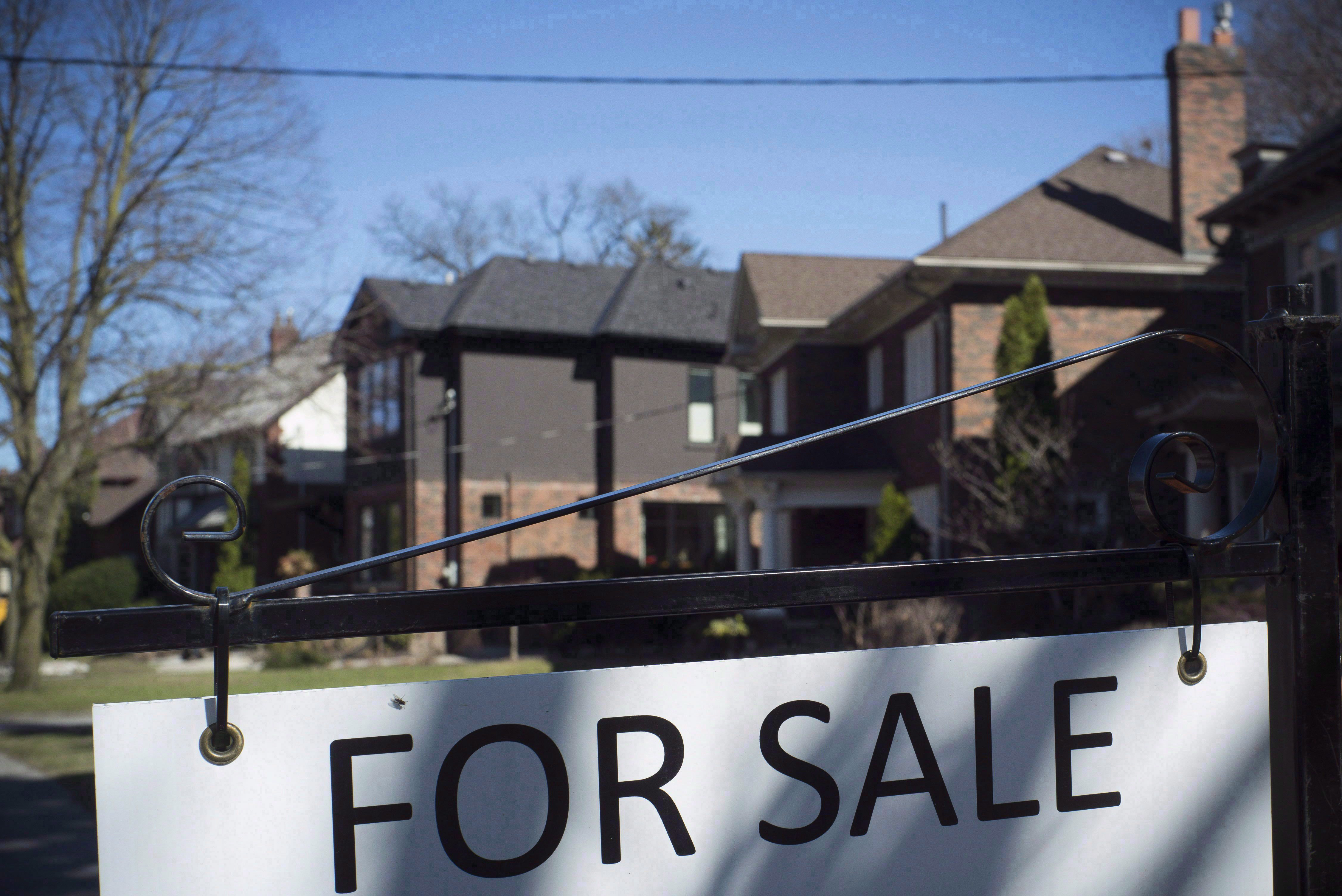 A "For Sale" sign is shown in front of west-end Toronto homes Sunday, April 9, 2017. The Toronto Real Estate Board says area home sales were up 12 per cent from September to October, pointing to a stronger fall market. THE CANADIAN PRESS/Graeme Roy.