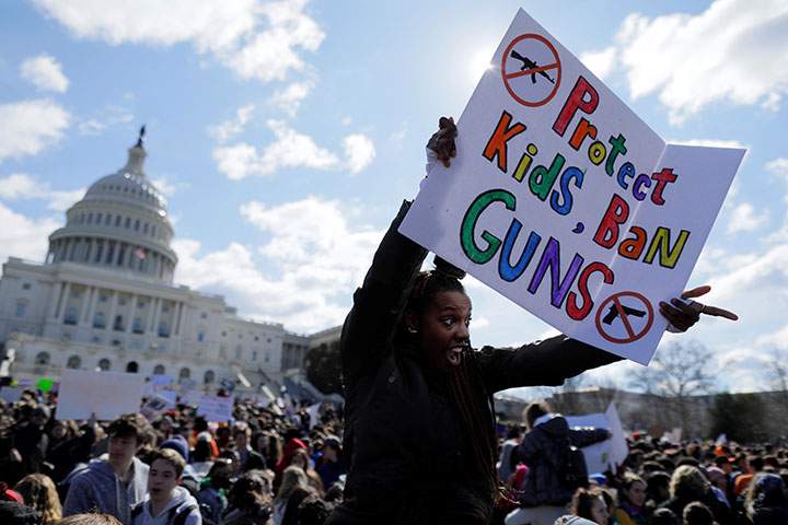 A Washington, DC high school student joins with others walking out of classes to demand stricter gun laws outside the U.S. Capitol in Washington, March 14, 2018.