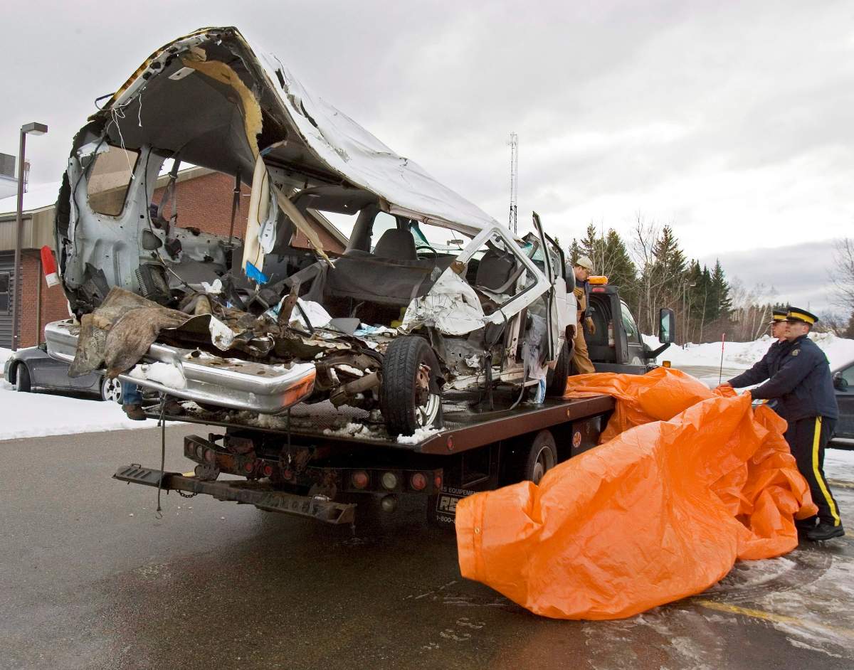 RCMP officers remove a tarp covering a van that was carrying the Bathurst High School boys’ basketball team that collided with a transport truck while returning from a game in Bathurst, N.B., on January 12, 2008.