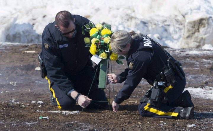 Members of the RCMP lay flowers at the intersection of a crash site near Tisdale, Sask., Sunday, April, 8, 2018.
