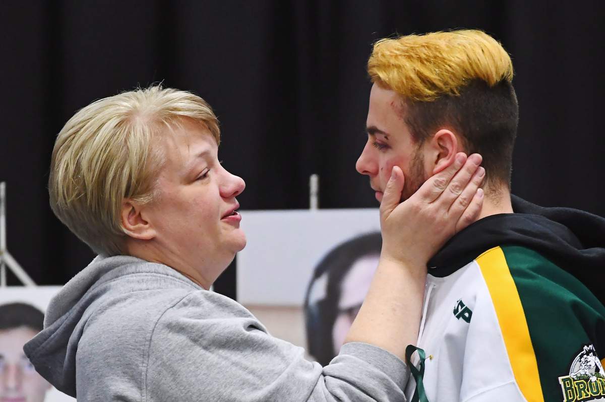 Humboldt Broncos' Nick Shumlanski is comforted by a mourner during a vigil at the Elgar Petersen Arena, home of the Humboldt Broncos, to honour the victims of a fatal bus accident in Humboldt, Sask. on Sunday, April 8, 2018.