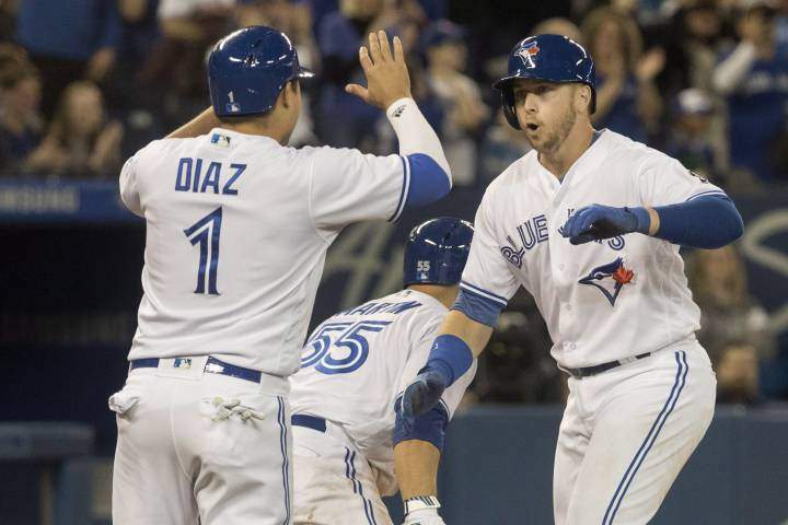 Toronto Blue Jays' Justin Smoak, right, is greeted at home plate by teammates Aledmys Diaz and Russell Martin after he hit a grand slam against the New York Yankees in the eighth inning of their American League MLB baseball game in Toronto on Sunday April 1, 2018.