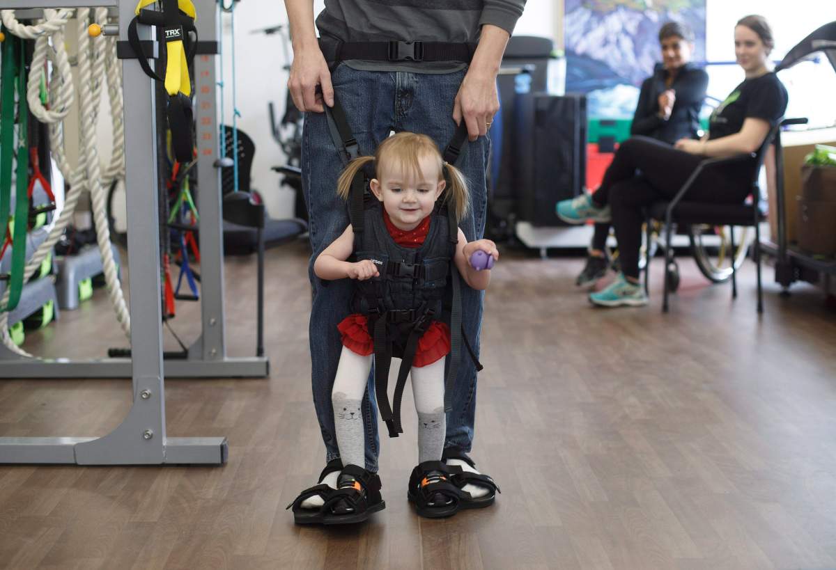 Evelyn Moore is hooked up to her dad Brad Moore as they take part in a walking exercise at the ReYu Paralysis Recovery Centre in Edmonton Alta, on Wednesday April 4, 2018.