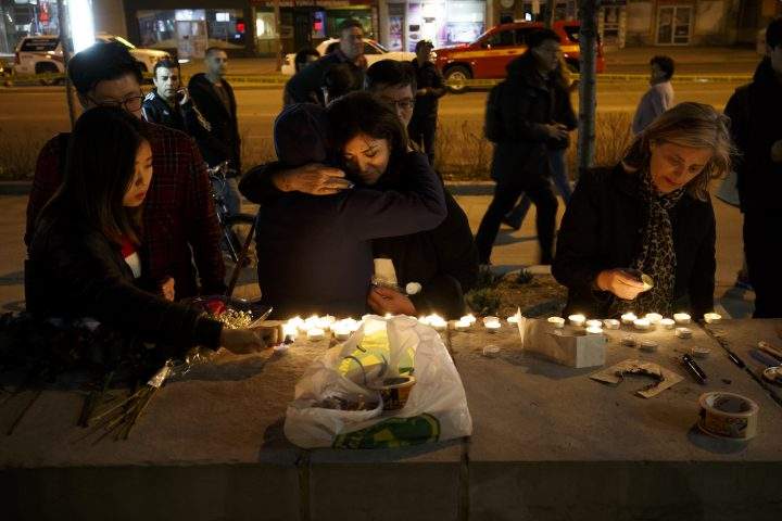 People embrace as they lay candles and leave messages at a memorial for victims of an attack in Toronto. Getty Images