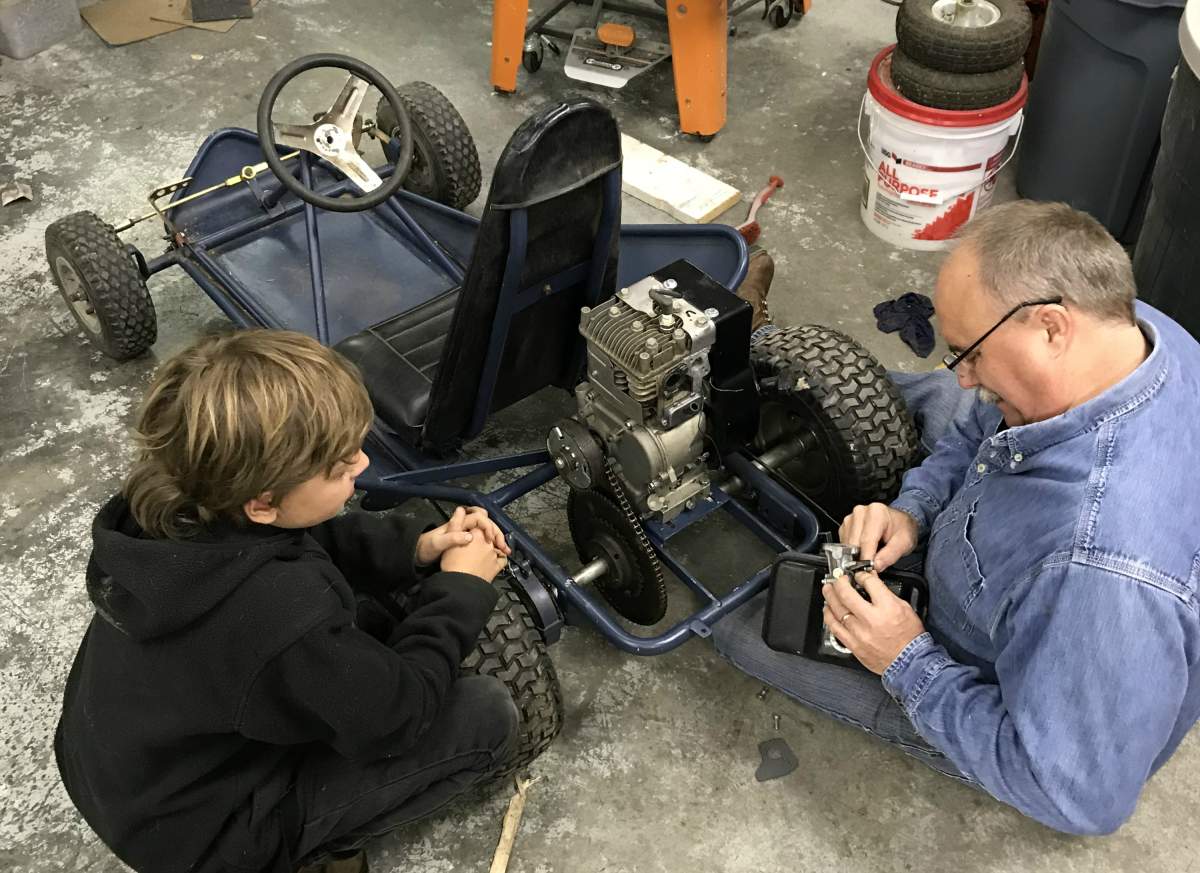 Bodhi Davey, left, and grandfather Walt Harris work on the boy’s go-kart.