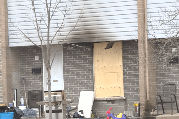 The front window of a townhouse on Curtis Cres. in Kingston is boarded up after a Thursday morning fire left its 7 occupants homeless.