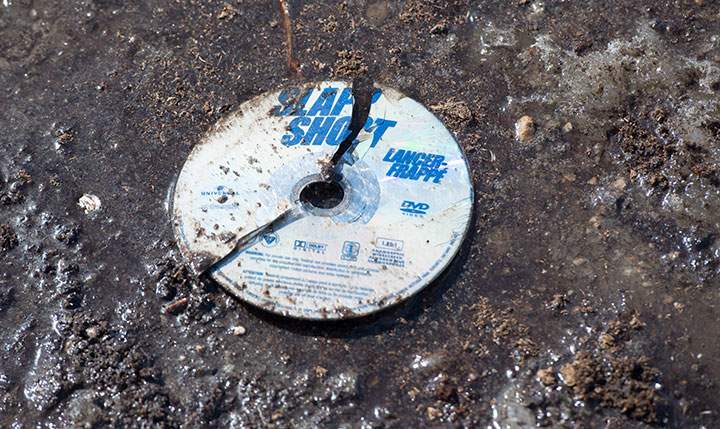 A broken DVD of the hockey movie Slap Shot is seen in the mud at the intersection of a crash site near Tisdale, Sask., Sunday, April 8, 2018.