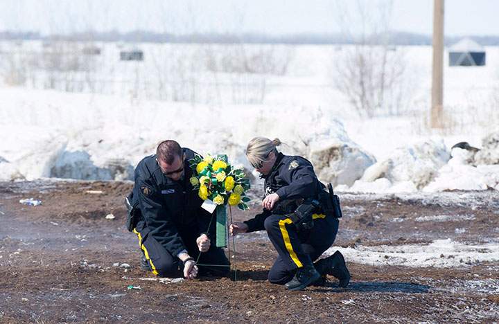 Members of the RCMP lay flowers at the intersection of a crash site near Tisdale, Sask., Sunday, April, 8, 2018.