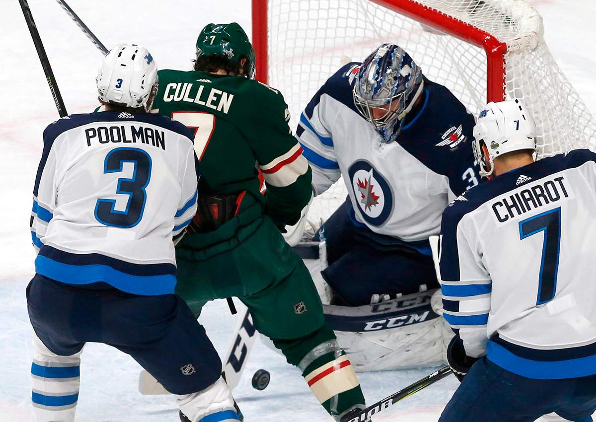 Winnipeg Jets goalie Connor Hellebuyck stops a scoring attempt by Minnesota Wild's Matt Cullen, second from left, during the second period of Game 4 of an NHL hockey first-round playoff series Tuesday, April 17, 2018, in St. Paul, Minn. 