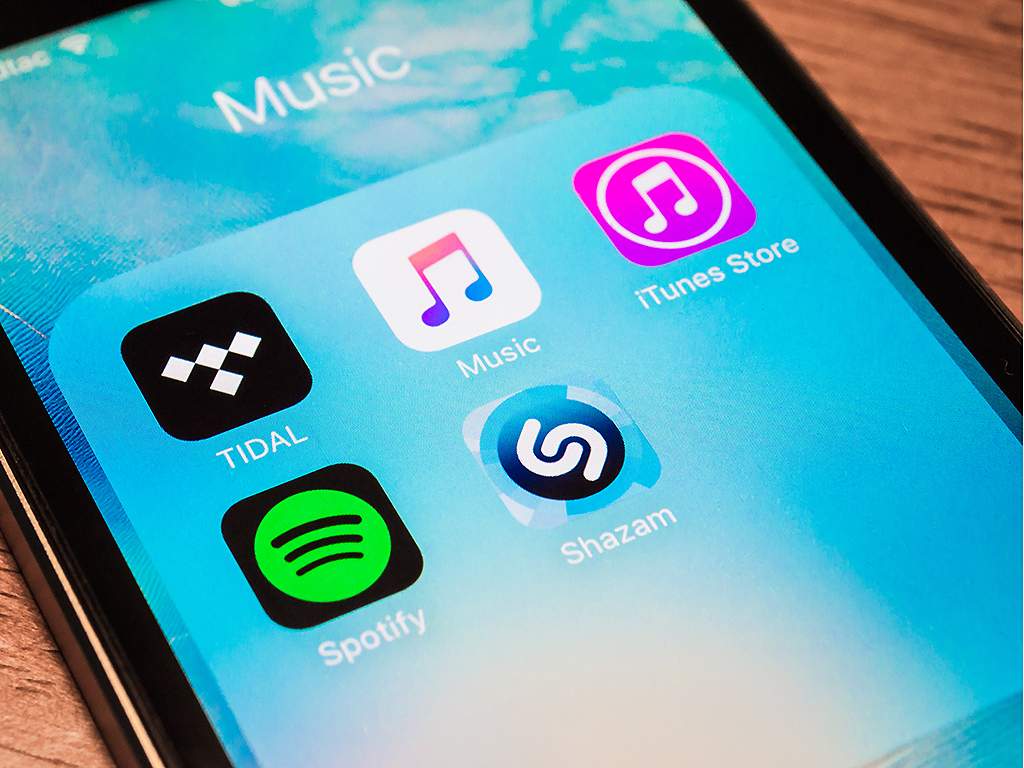An Apple iPhone 5s showing its screen with popular music applications, in June 2016.