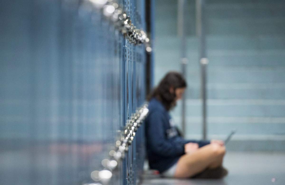A student works on her laptop next to lockers at Dawson College in Montreal.