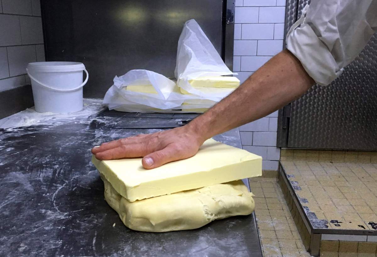 French baker Stephane Louvard puts his hand on a slice of butter in his Paris bakery, Friday, Oct. 20, 2017. French pastries and butter have become so popular abroad that the increased demand led to a mini shortage of the dairy product in French supermarkets.