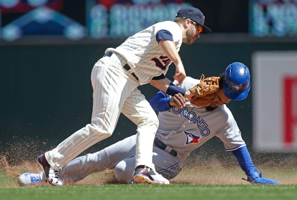 Toronto Blue Jays' Teoscar Hernandez, right, loses his helmet as he is tagged out by Minnesota Twins second baseman Brian Dozier during a steal attempt in the eighth inning of a baseball game Wednesday, May 2, 2018, in Minneapolis. The Twins won 4-0.