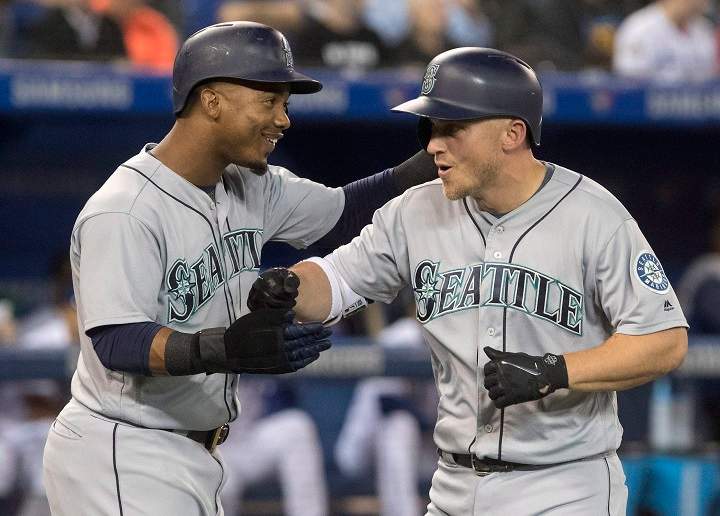 Seattle Mariners' Kyle Seager celebrates with teammate Jean Segura after hitting a grand slam against Toronto Blue Jays starting pitcher J.A. Happ in first inning League MLB baseball action in Toronto on Thursday.