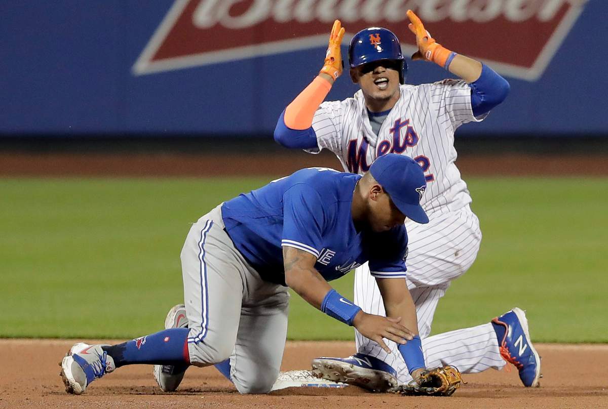 New York Mets' Juan Lagares motions to the dugout after advancing to second base following his single, ahead of the tag from Toronto Blue Jays second baseman Yangervis Solarte during the fourth inning of a baseball game, Tuesday, May 15, 2018, in New York.