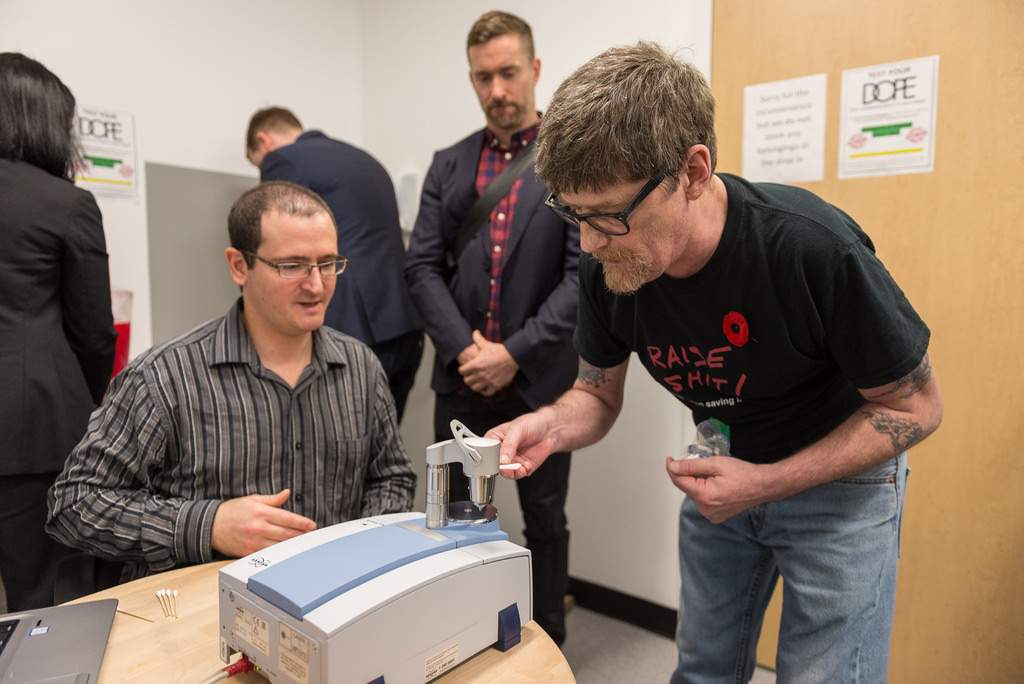 Health workers use an FTIR spectrometer to test drug samples.