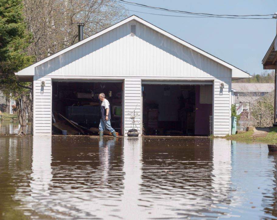 Rick Banks walks past his garage while cleaning up debris from his property located along route 105 in Maugerville, N.B, Wednesday, May 9, 2018.