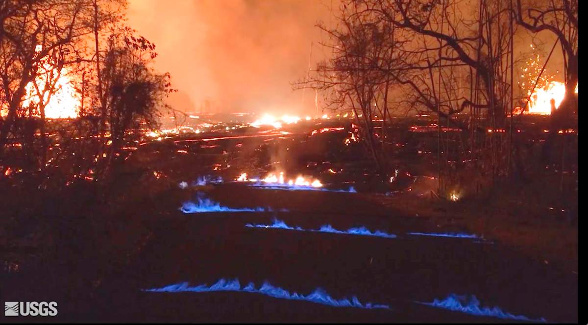 This photo from video from the U.S. Geological Survey shows blue burning flames of methane gas erupting through cracks on Kahukai Street in the Leilani Estates neighborhood of Pahoa on the island of Hawaii during the overnight hours of Wednesday, May 23, 2018. When lava buries plants and shrubs, methane gas is produced as a byproduct of burning vegetation. Methane gas can seep into subsurface voids and explode when heated, emerging from cracks in the ground several feet away from the lava.