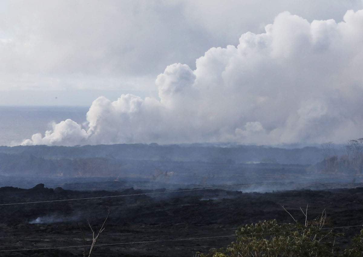 A steam plume rises (TOP) from lava entering the Pacific Ocean, after flowing to the water from a Kilauea volcano fissure, on Hawaii’s Big Island on May 20, 2018 in Kapoho, Hawaii.