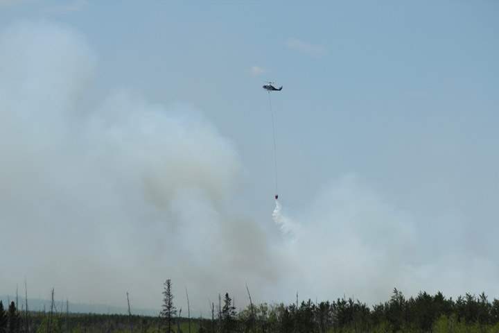 An aerial unit drops water on a wildfire burning out of control near Holbein, Sask.