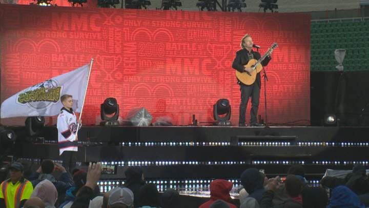 A boy holds a Humboldt Broncos flag as Jack Semple performs “Hallelujah” in Regina on May 17, 2018 at the opening ceremony of the Memorial Cup.
