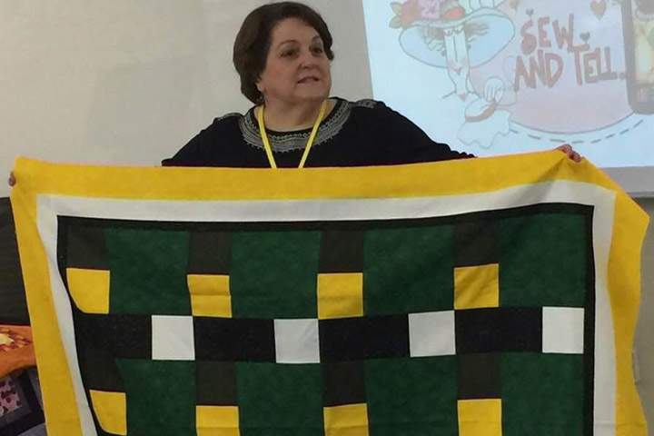 Dale Gilbert holds a quilt in Qatar in this undated handout photo. It's 11,097 kilometres from Doha to Humboldt, Saskatchewan but the fatal crash between a bus carrying junior hockey players hit close to home for Dale Gilbert and her husband Scott. 