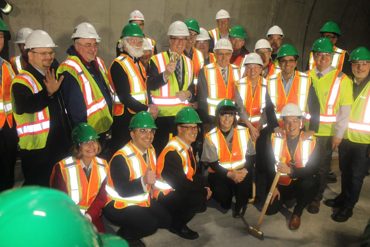 Mayor Jim Watson and other local politicians hold up one of the ceremonial rail clips signifying the completion of the LRT track on Friday.