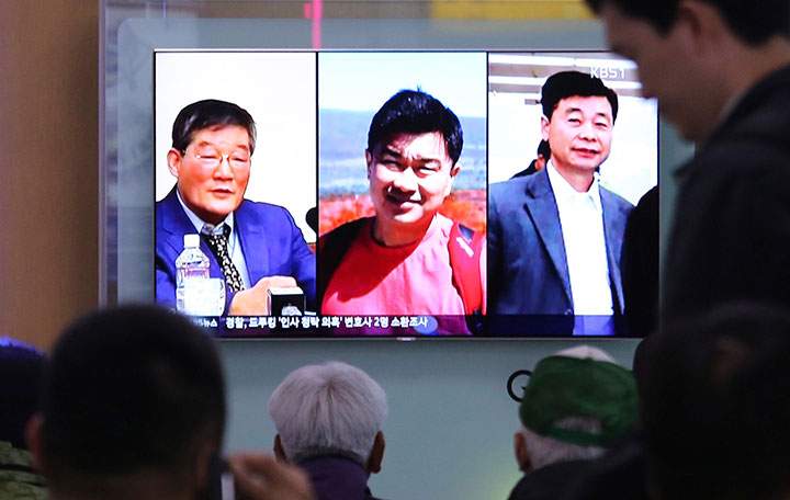People watch a TV news report on screen, showing portraits of three Americans, Kim Dong Chul, left, Tony Kim and Kim Hak Song, right, detained in the North Korea