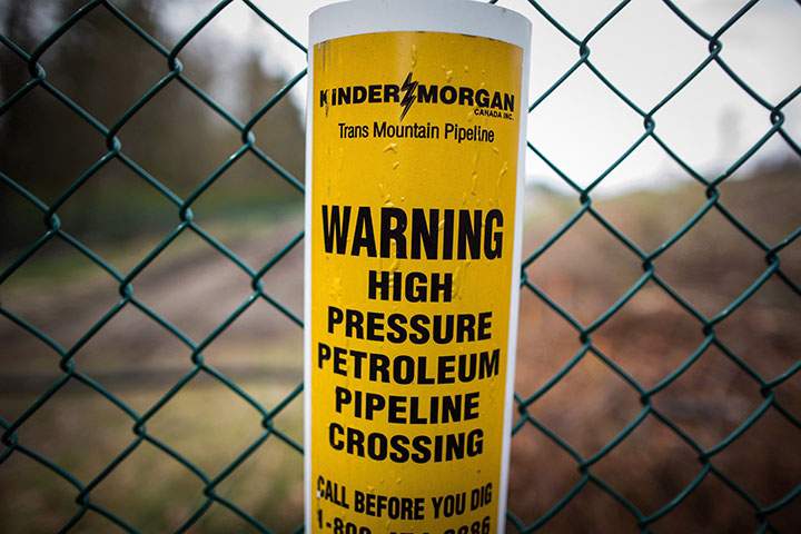 A sign warning of an underground petroleum pipeline is seen on a fence at Kinder Morgan's facility where work is being conducted in preparation for the expansion of the Trans Mountain Pipeline, in Burnaby, B.C., on Monday April 9, 2018. 