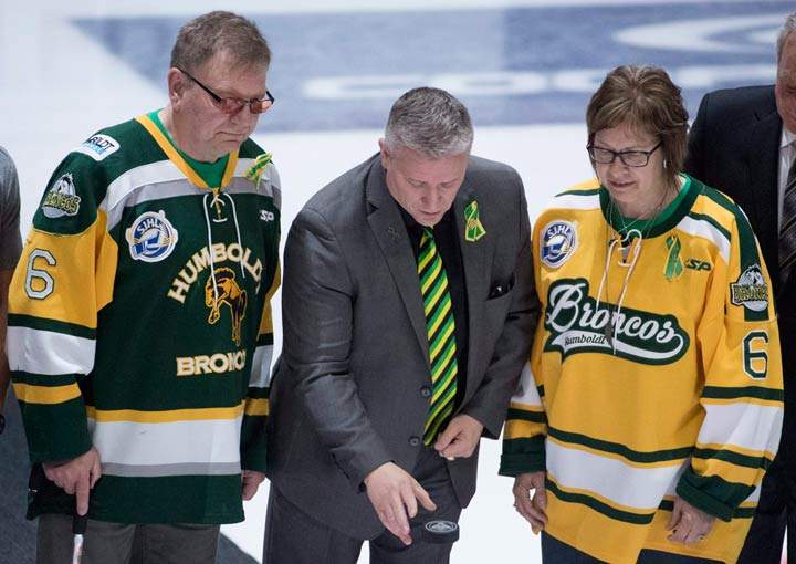 Humboldt Broncos president Kevin Garinger, centre, and team athletic therapist Dayna Brons’s mom Carol Brons as dad Lyle take part in a ceremonial puck drop.