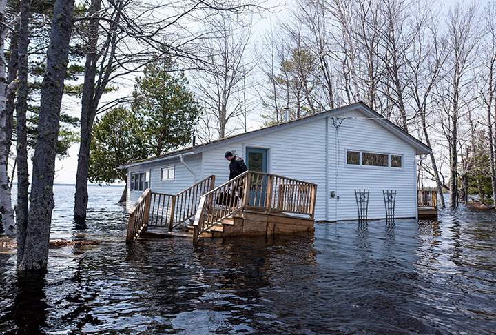 A man carries a bag of clothing before leaving his home as floodwaters from the Saint John River continue rising in Grand Lake, N.B. on Wednesday, May 2, 2018.