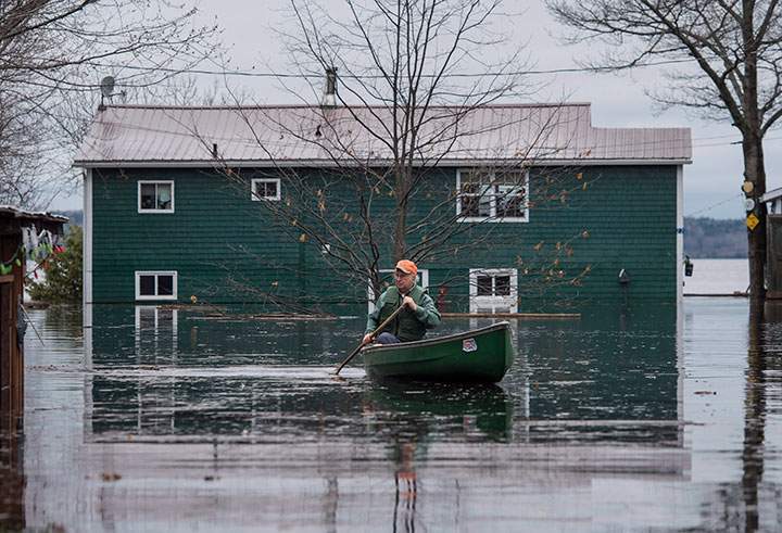 A man paddles in front of a flooded home on Grand Lake, N.B. as floodwaters continue to rise from the Saint John River on Tuesday, May 1, 2018.